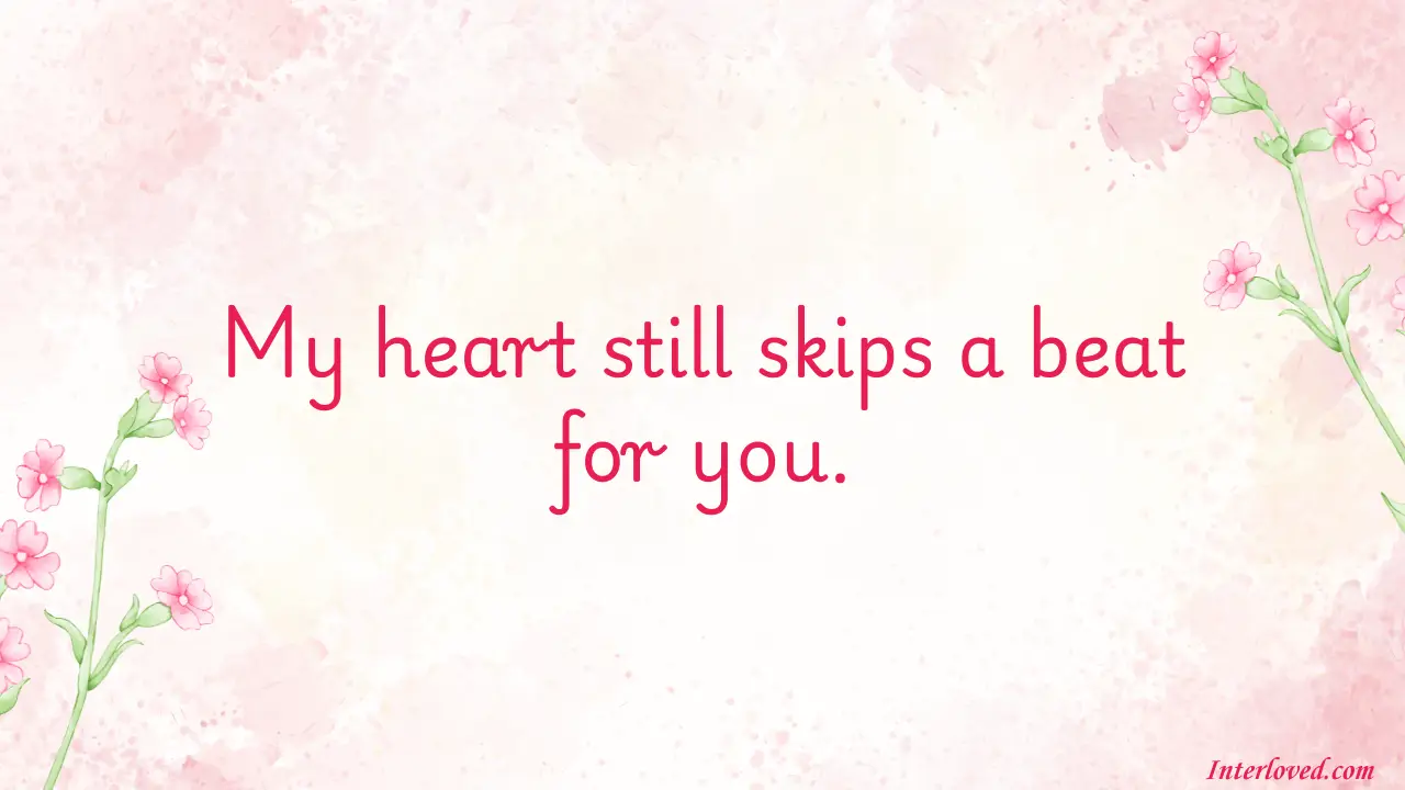 100 Short Love Messages to Send Daily - Fresh Love Texts A romantic message on a soft pink watercolor background with delicate pink flowers on the left and right edges. The message reads: "My heart still skips a beat for you."